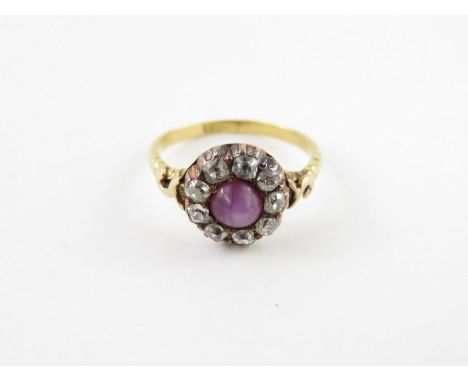 A late Victorian star ruby and diamond cluster ring, stamped ‘18ct’, the round cabochon, approximately 5.5mm diameter, enclos