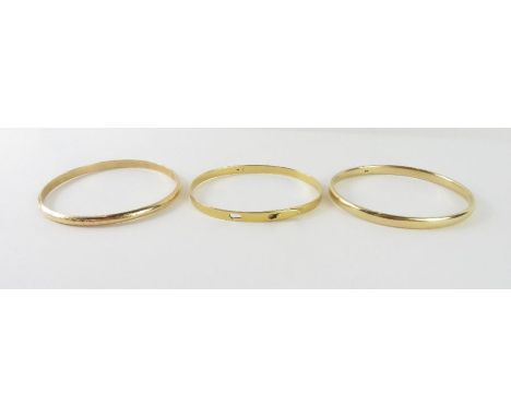 Two solid bangles, one patterned, both marked '14k', 19.36g gross; and an unmarked slim buckle style bangle, tests as 14-15ct