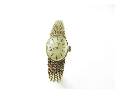 A ladies vintage Omega 9ct gold wrist watch, the oval champagne dial with black baton hour markers and hands, Omega button, o