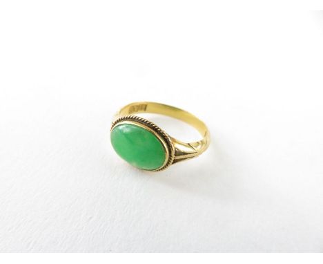 A single oval cabochon cut jadeite ring, the stone approximately 10mm x 7.5mm, marked '18;, finger size K 1/2, 2.79g gross