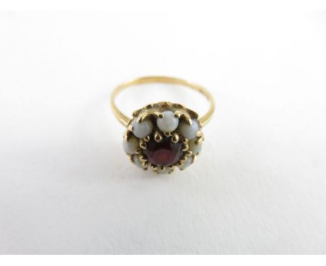 A garnet and opal cluster ring, the central garnet approximately 5.5mm, surrounded by eight round cabochon cut opals, marked 