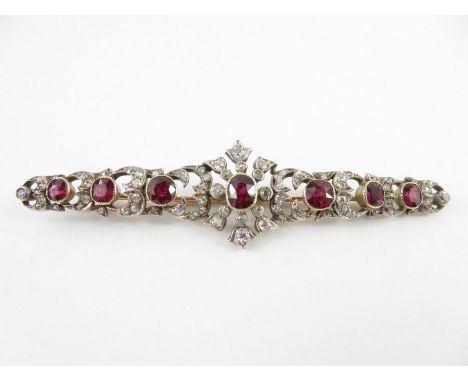 A diamond and ruby brooch, the unmarked mount set with seven graduated oval cut rubies and old single and old brilliant cuts 