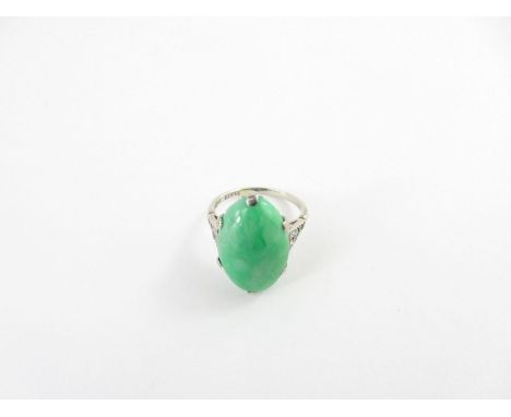 A jade and diamond ring, the white mount stamped ’18ct’ and ‘Plat’, the oval cabochon 19mm by 12mm, with an old brilliant cut