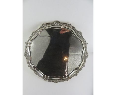 A silver salver, J. Gloster Ltd, Birmingham 1957, of circular shaped outline, with leaf, shell and scroll border, on bracket 