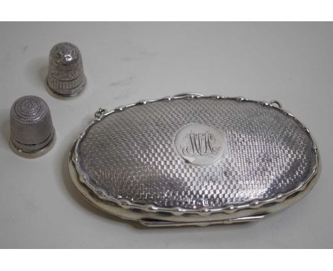 A George V lady's silver purse of oval form having engine turned decoration and monogrammed cartouche with leather partitione