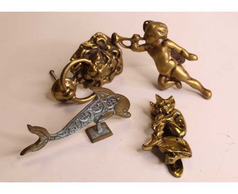 A modern brass door-knocker in the form of a lions head; together with two others being a cherub with trumpet and an imp on a