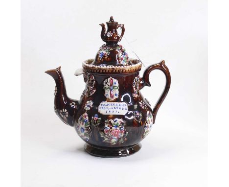 A late Victorian treacle glazed bargeware teapot and cover, having applied floral decoration, the plaque impressed To John &a