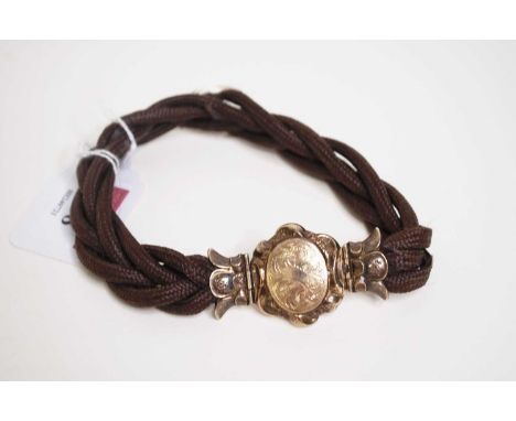 A braided mourning bangle on a 19th century pinchbeck clasp with locket containing a photograph of a young girl