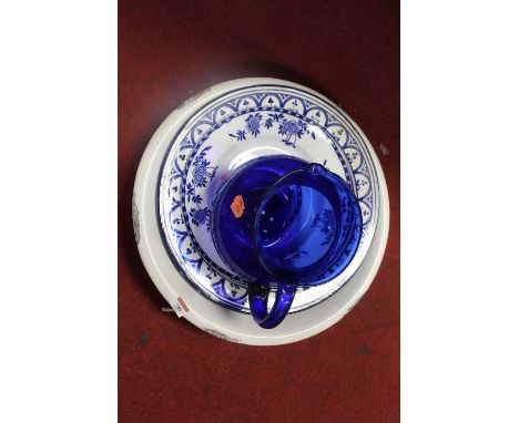 A white glazed ceramic wash bowl together with two blue &amp; white chargers and a further blue glass jug (4)