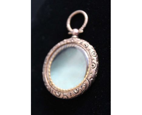 A Victorian pinchbeck pendant, having engine turned back cover and leaf and flower chased border, dia.38mm
