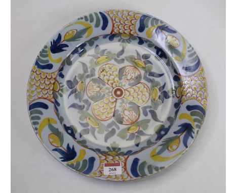 An 18th century English Delft charger on a light blue ground, handpainted with flowers in shades of blue, orange and yellow, 