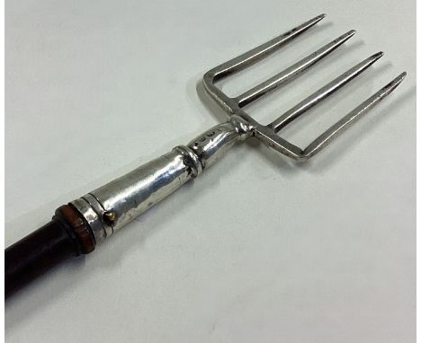 A large 19th Century Georgian silver toasting fork with wooden handle. Approx. 100 grams of gross weight. Est. £100 - £150.