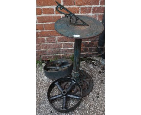 A cast iron sundial on a stand and two railway wheels