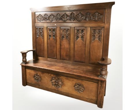 An Arts and Crafts carved oak panel back storage settle, 192 cm x 43 cm x 178 cm.