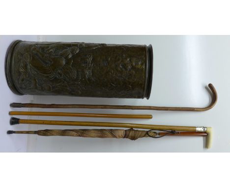 An umbrella stand with embossed scene, a walking cane with silver collar, lady's umbrella, swagger stick and walking stick