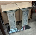 A pair of mirrored pedestals with square top and column on a spreading foot