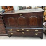 An 18th century oak mule chest with a hinged top and three panel front enclosing a wine rack above