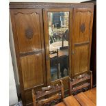 An Edwardian mahogany three door wardrobe with a central mirrored door on square legs together