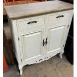 A cream painted side cabinet with a stripped top above two drawers and two cupboards on shaped legs