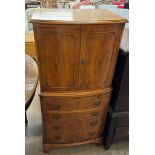 A yew drinks cabinet with a pair of cupboard doors above a slide,