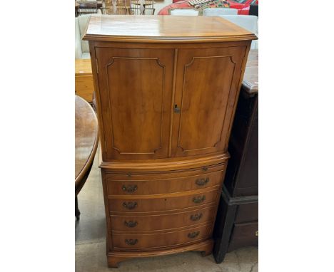 A yew drinks cabinet with a pair of cupboard doors above a slide, drawer and cupboard base 