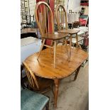 A pine dining table together with a set of four Ercol stick back dining chairs