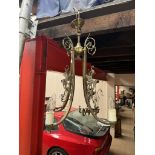 A brass three branch chandelier with scrolling leaves and dragon castings