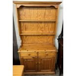 A pine dresser with a moulded cornice above two shelves,