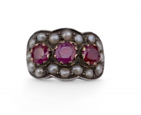 Indian Circa 1930s A ruby and half pearl dress ring. The front set with three slightly graduated circular cut rubies, within 