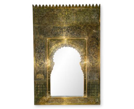 A brass wall mirror with castellated pediment, over panels to the top, side and base with Quranic script, inset with brass mi