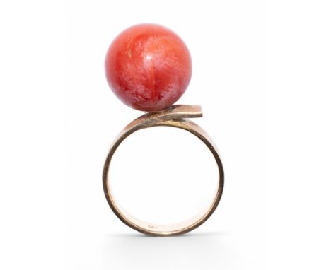Continental c.1960 A red coral and gold dress ring The coral bead perched on a brushed finish wrap around hoop  Ring size: M 