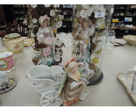 A pair of early 20th continental bisque figures on foliate stands, one with glass dome and another similar figure, lady with 