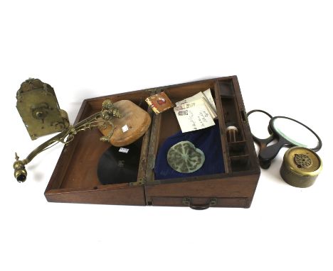 A wooden box (previously a writing slope) containing an assortment of collectables. Including clock movements, a set of mirro