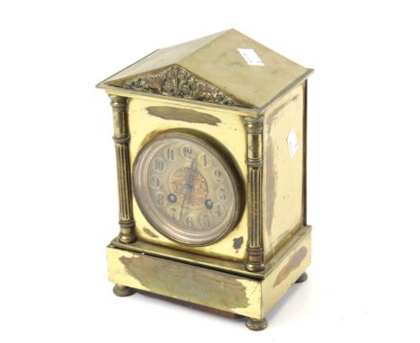 A 20th century brass mantle clock. The dial with Arabic numerals and pierced details, the case with a carved pediment, raised