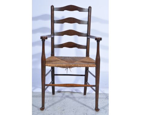 Oak ladder-back elbow chair, rush seat turned legs, width 57cm.