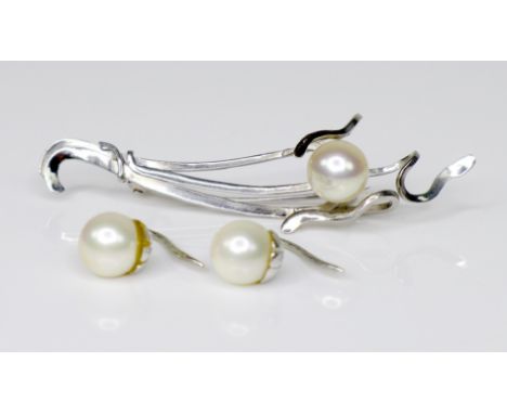 An 18ct white gold and pearl brooch of naturalistic form, 51.1mm long, 3.6g, together with a pair of pearl earrings with whit