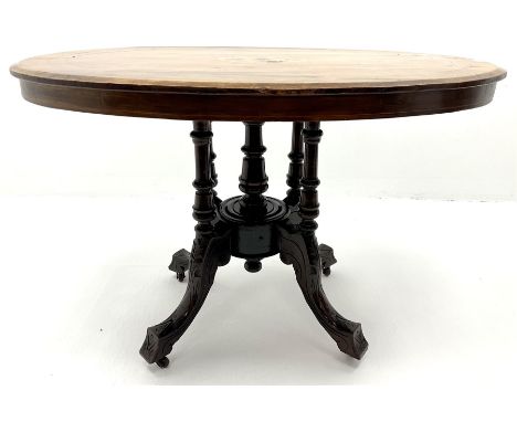 Edwardian inlaid walnut oval pedestal salon table, four turned supports joined by central finial on acanthus carved shaped su