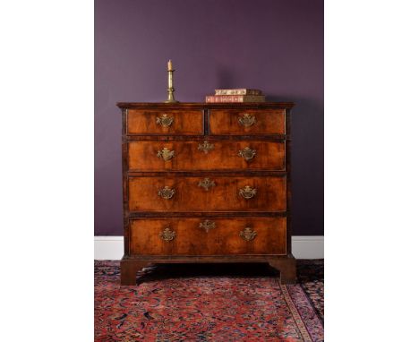 A George II walnut chest of drawers, circa 1735, feather banded throughout, the quarter veneered and crossbanded top above tw
