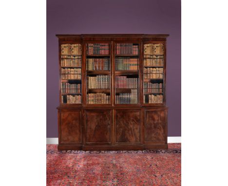 A George III mahogany breakfront library bookcase, circa 1800, the stepped cornice above a pair of glazed doors flanked by a 