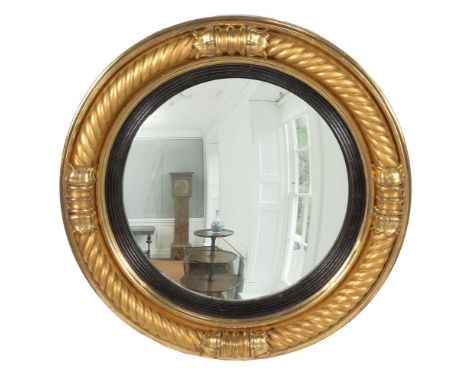 A George III giltwood convex mirror, circa 1810, by Thomas Fentham, the oval mirror plate within a reeded ebonised slip, the 