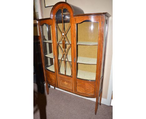 An Edwardian inlaid mahogany china cabinet, the central domed glazed panel flanked by two glazed panel doors enclosing silk l