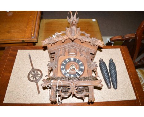 A carved Black Forest style cuckoo clock with buck head above roman dial.