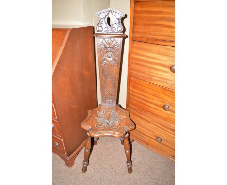 A carved oak spinning stool, carved with foliate motifs and mask and raised on turned legs.