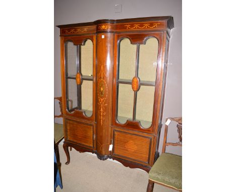 An Edwardian inlaid mahogany display cabinet, the flared cornice above swag decorated frieze, two glazed panel doors below ea