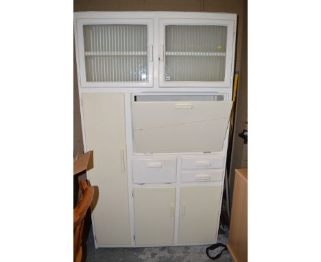 A white painted larder cupboard, with glazed panel doors above drop-flap and further cupboards and drawers.