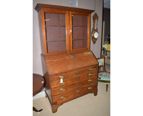 A George III mahogany bureau, with Edwardian top with flared dental cornice above a pair of glazed panel doors enclosing shel