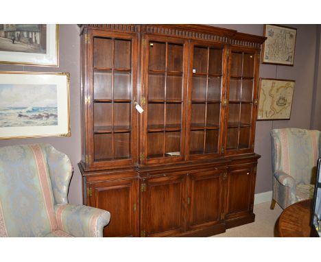 A Georgian style elm breakfront bookcase, the flared cornice above carved frieze, four glazed panel doors enclosing shelves, 