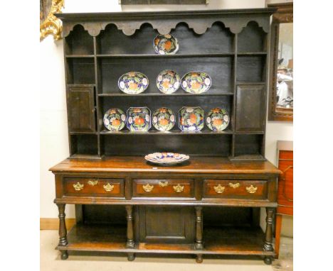 An antique Welsh style dresser with shelf and cupboard back, standing on base fitted three drawers with rack and cupboard und