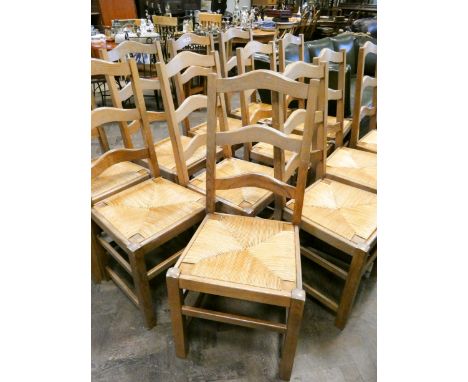 A set of thirteen French light oak ladder back dining room chairs with rush seats 