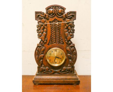 An eight day mantel clock in decorative leaf carved oak case 15" high 9 1/2 wide 